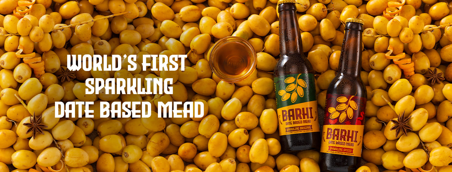 Barhi Original and Barhi Spiced date-based sparkling mead bottles placed on a bed of fresh yellow dates with text reading - World's First Sparkling Date Based Mead.