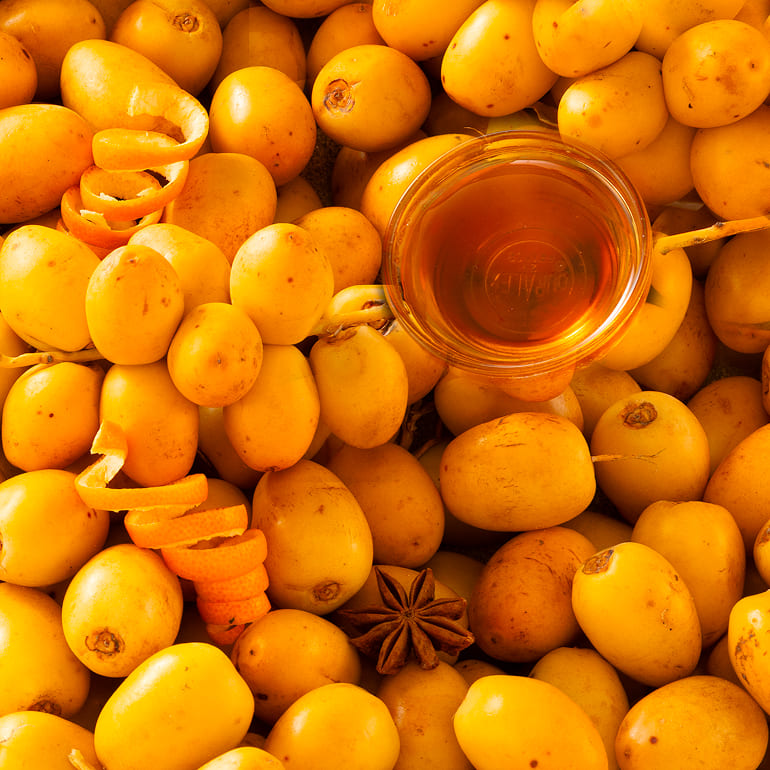 Top-down view of fresh yellow Barhi dates surrounding a small bowl of natural honey.